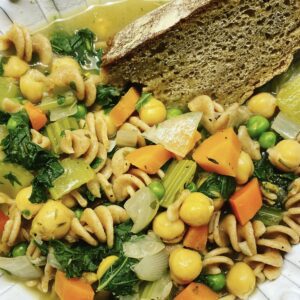 Chickpea Noodle Soup in a bowl with a slice of hearty bread dipped in the soup.