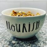 Overnight Oats in a bowl decorated with the word, "Nourish."