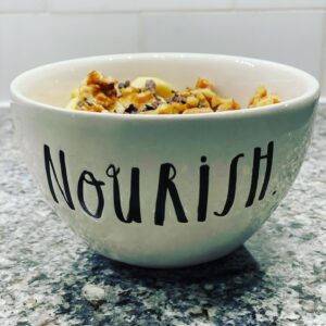 Overnight Oats in a bowl decorated with the word, "Nourish."