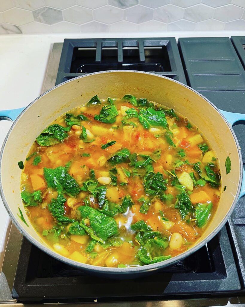 Comfy Kale and White Bean Soup in a stock pot on the stove.