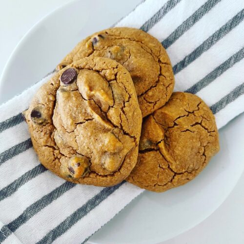 3 Chickpea Peanut Butter Chocolate Chip Cookies on a napkin on top of a white plate.