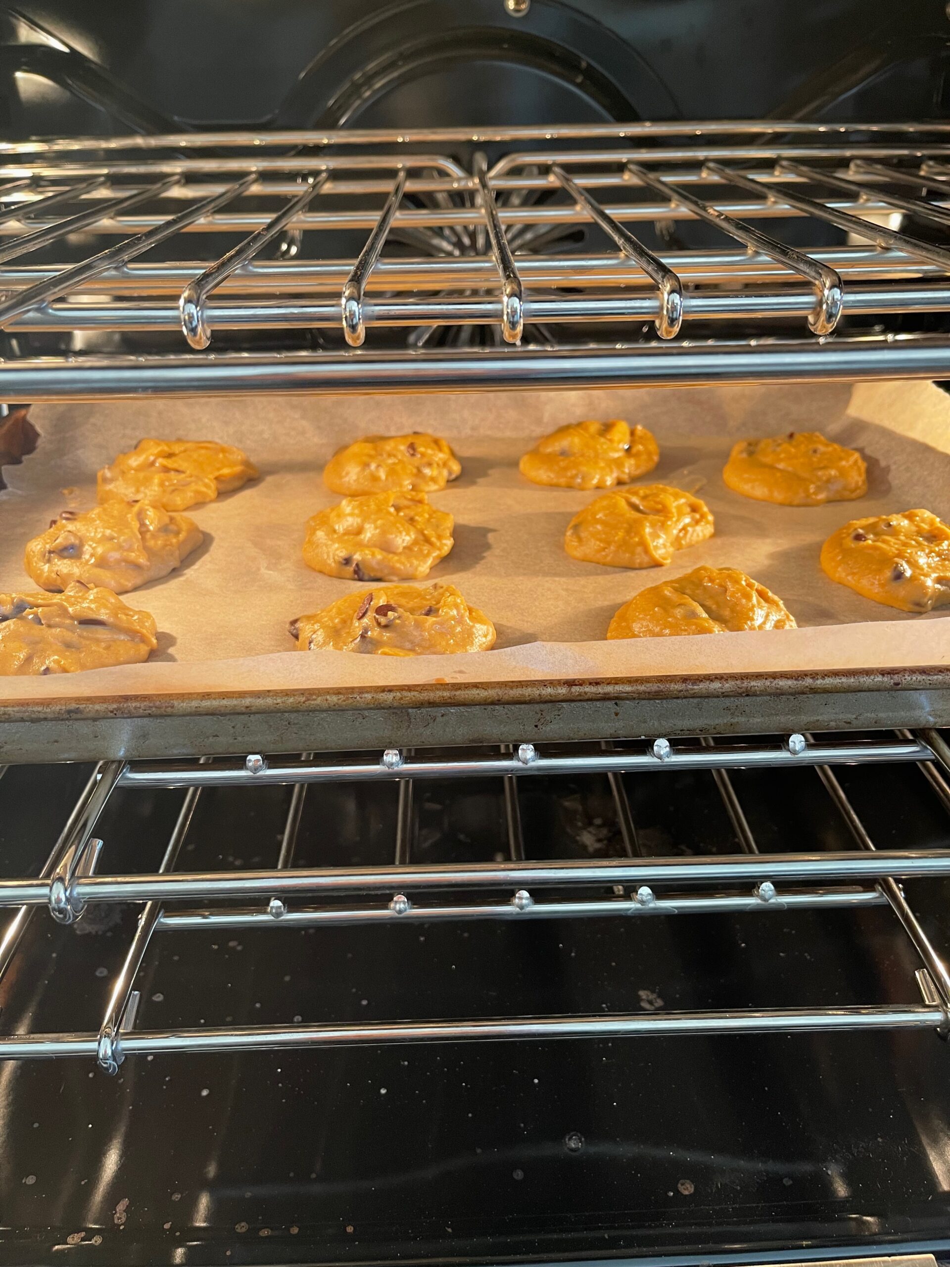 Chickpea Peanut Butter Chocolate Chip Cookies being baked in an oven on a cookie sheet.