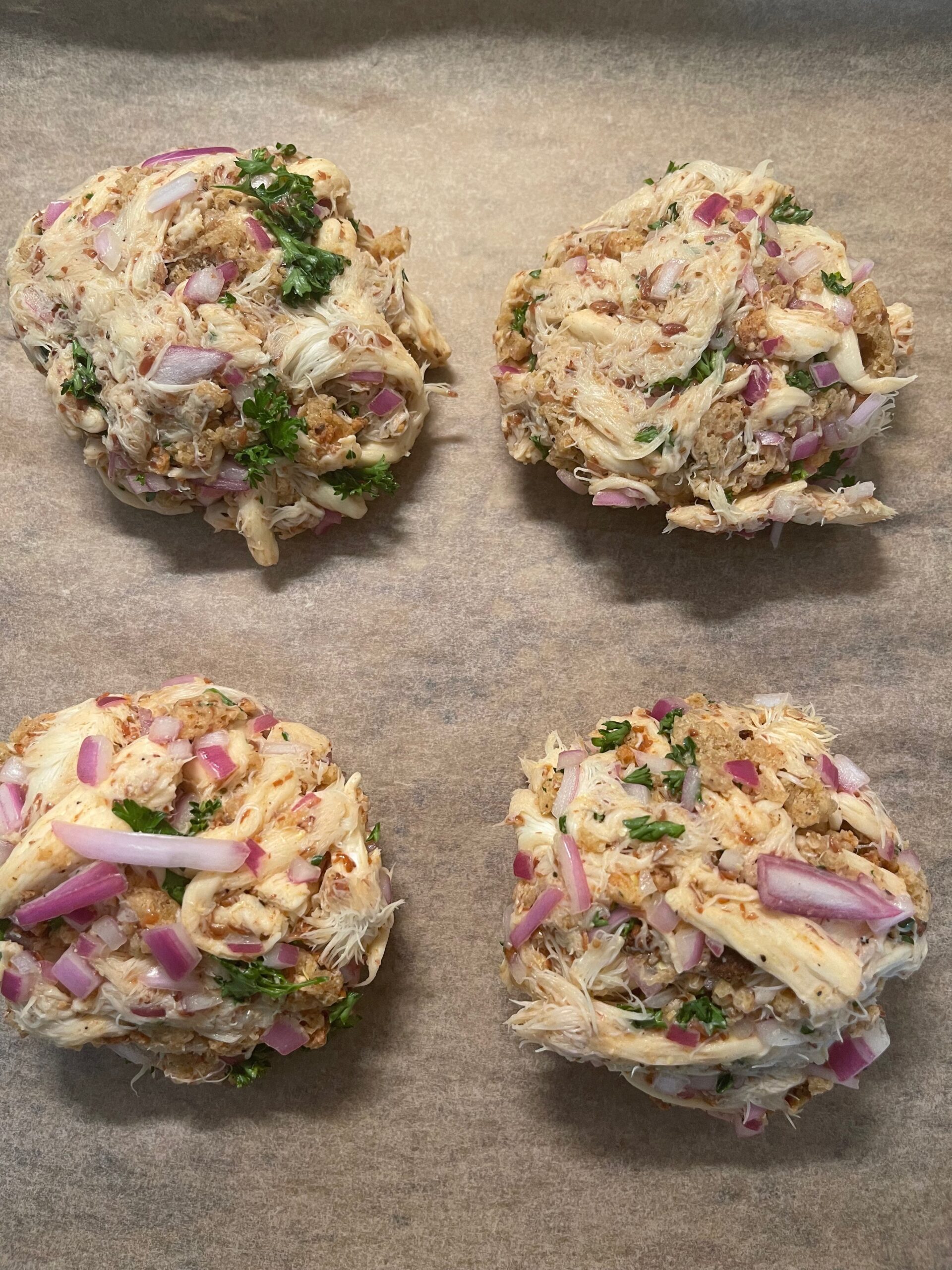 4 Vegan Mushroom Crab Cakes arranged on a pan, uncooked.